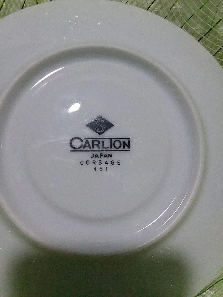 White ceramic plate with 'Carlton Japan Corsage 481' branding on a green surface.