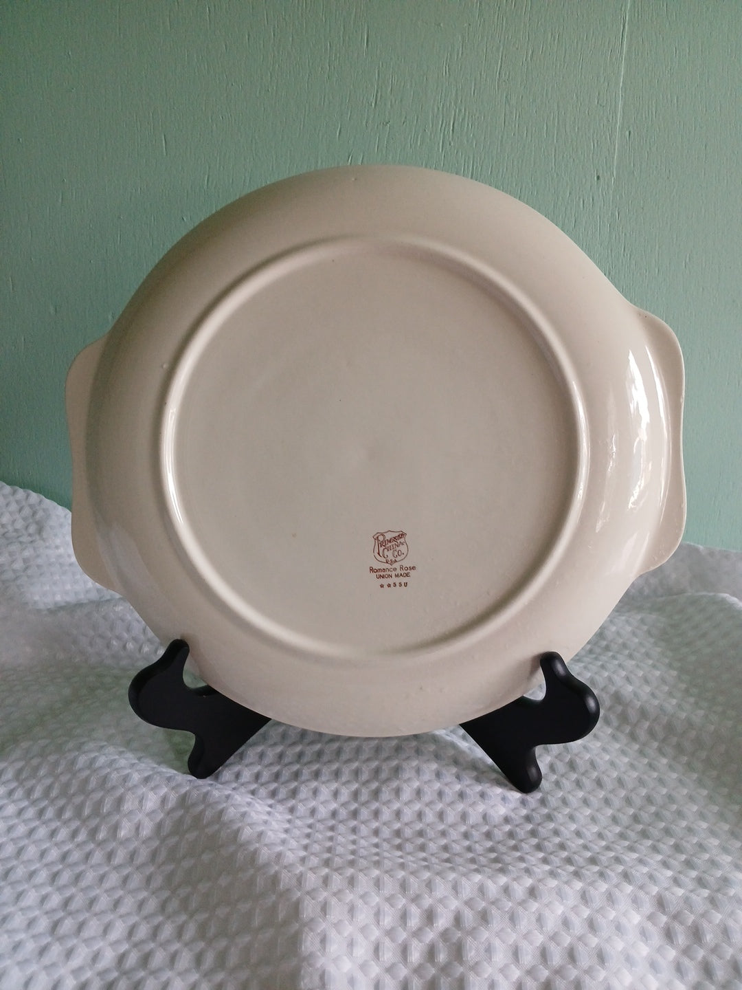White ceramic dish with handles on a light green background