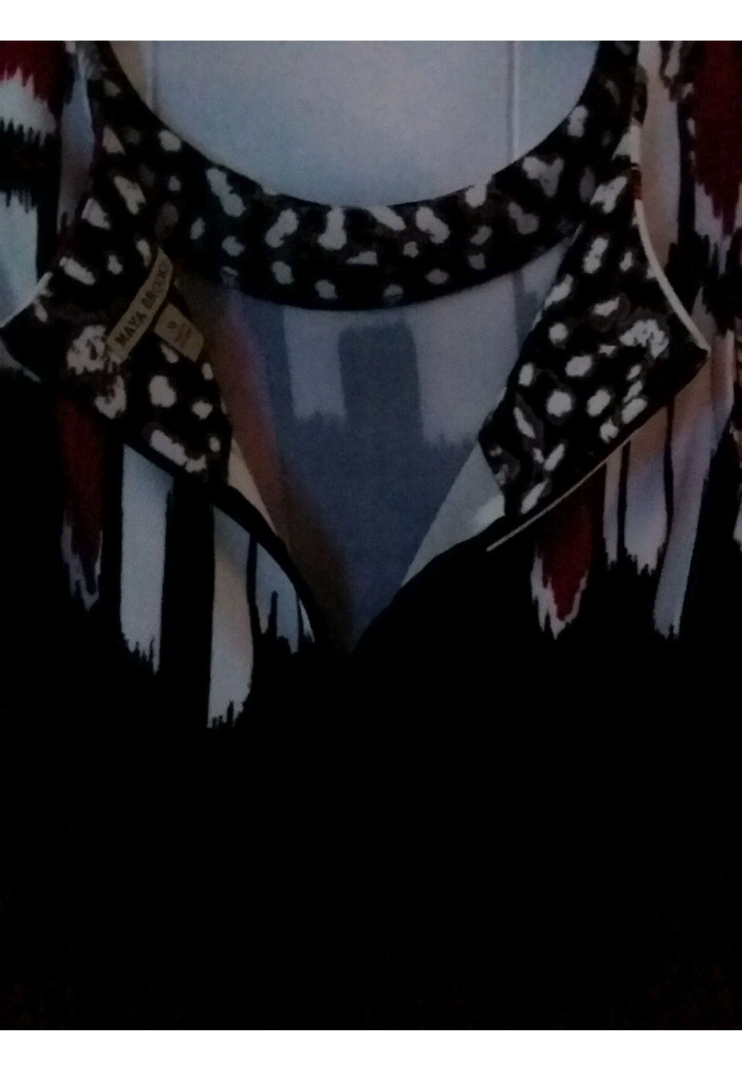 Close-up of a patterned scarf with a brand label on a dark background