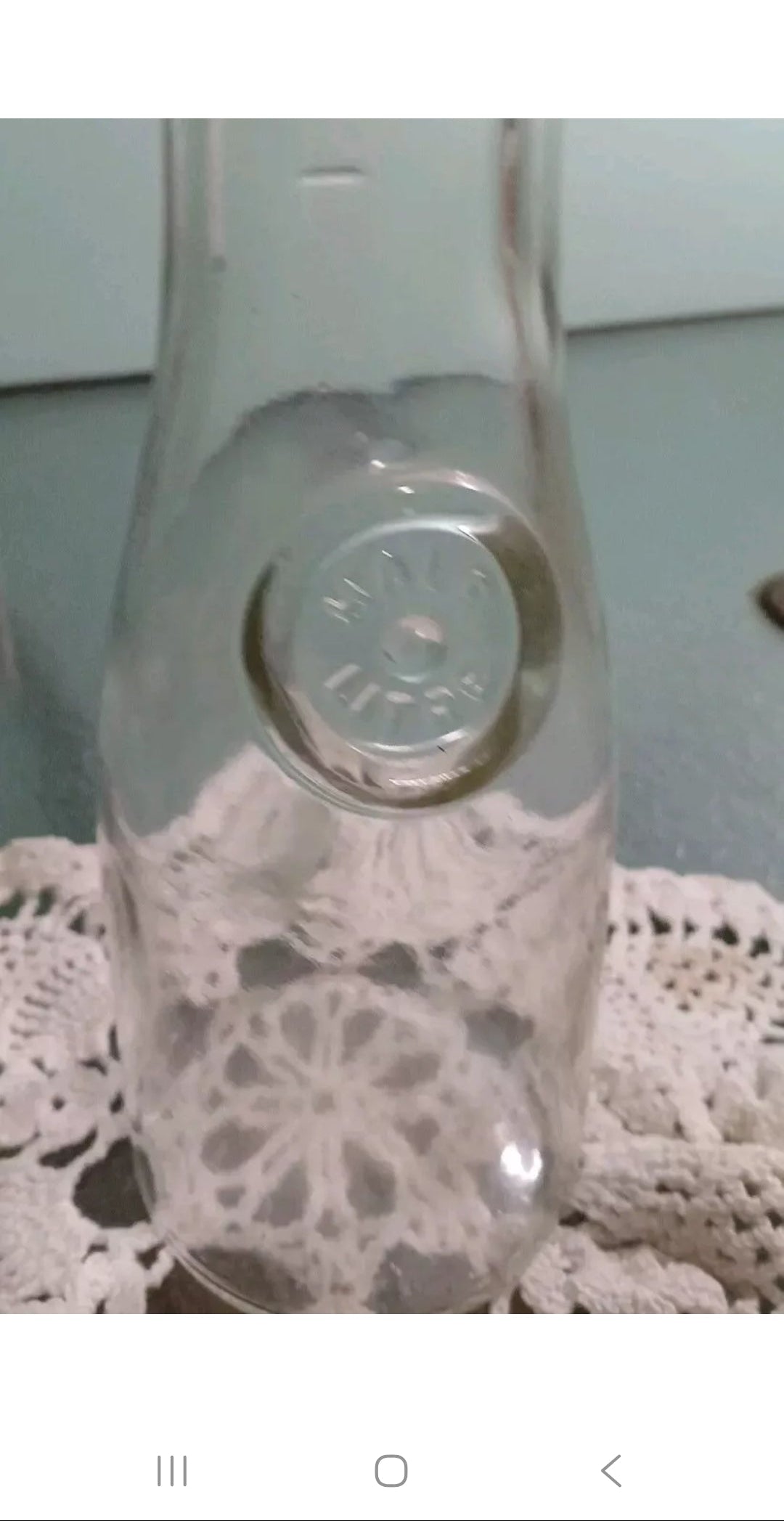 Clear glass bottle with a silver cap on a lace doily