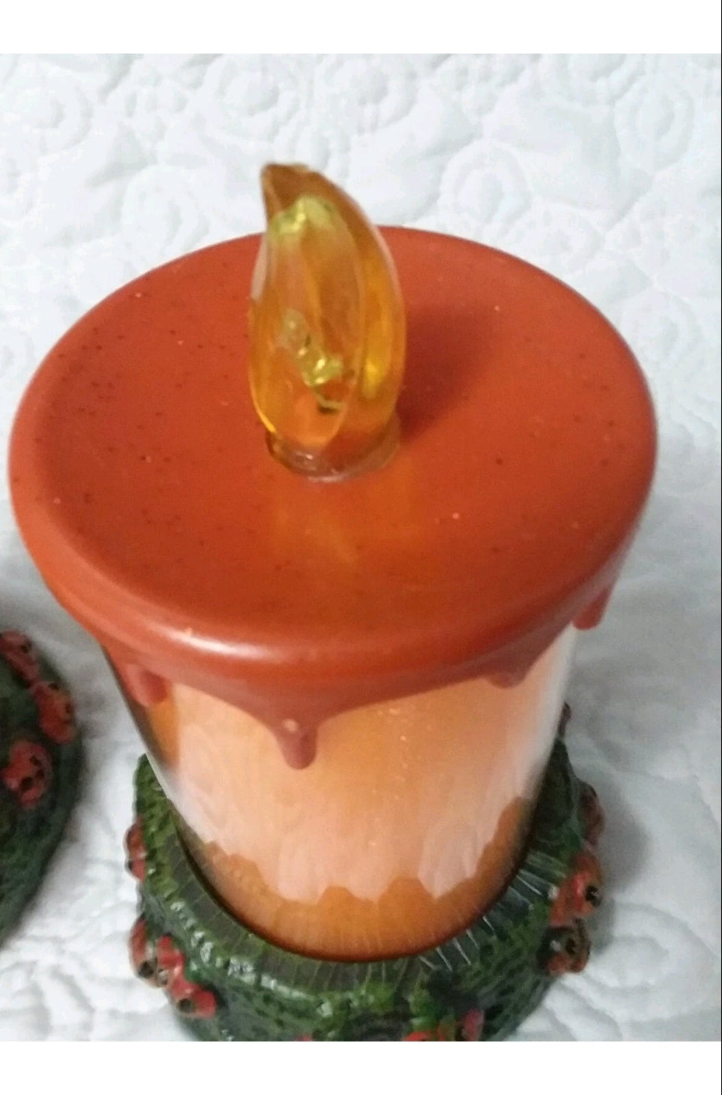 Decorative candle with a flame-shaped top on a textured white background
