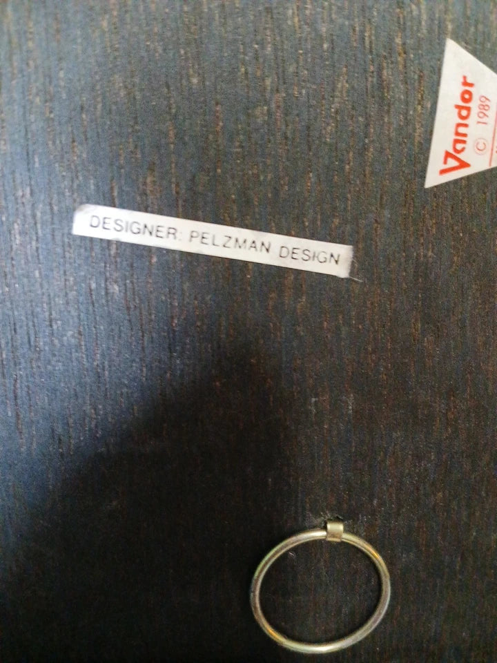 Gold ring on a dark wooden surface with 'Designer Felzman Design' label.