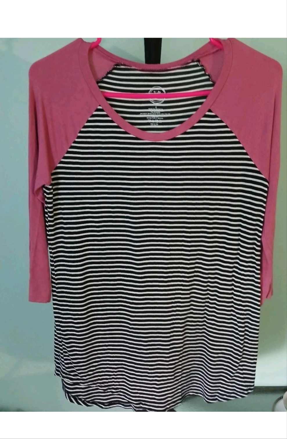 Black and white striped shirt with pink sleeves on a light blue background