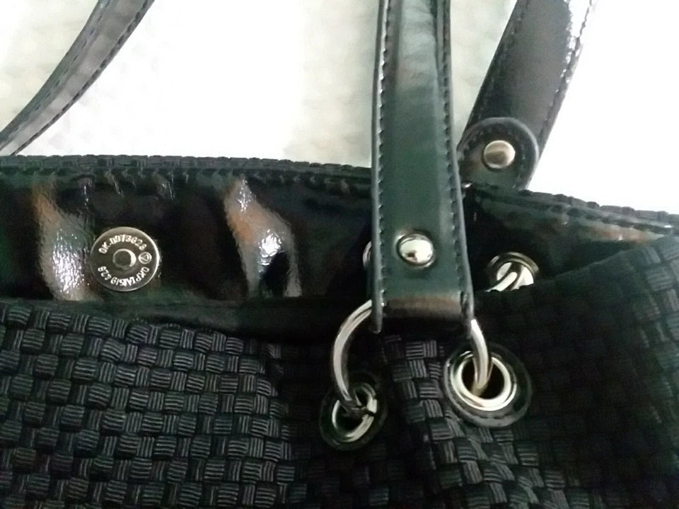 Close-up of a black handbag with a strap and metal ring detail.