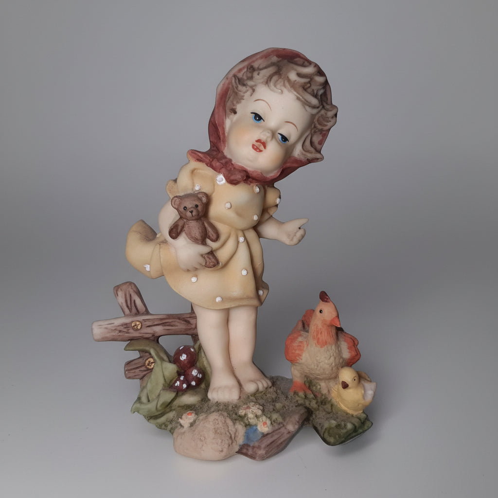 Vintage-style figurine of a child with a chicken on a decorative base