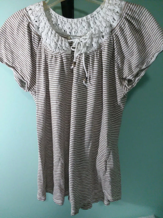 Striped blouse with lace details on a hanger against a teal wall