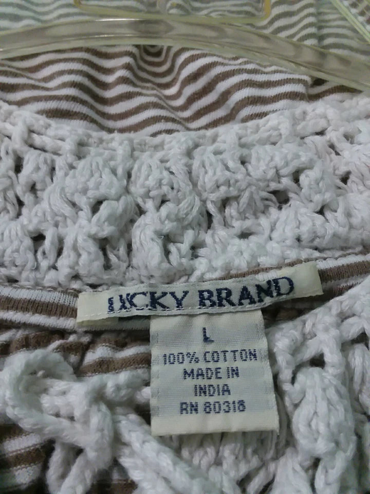 Close-up of a textured fabric with a 'Lucky Brand' tag showing size L and material details.
