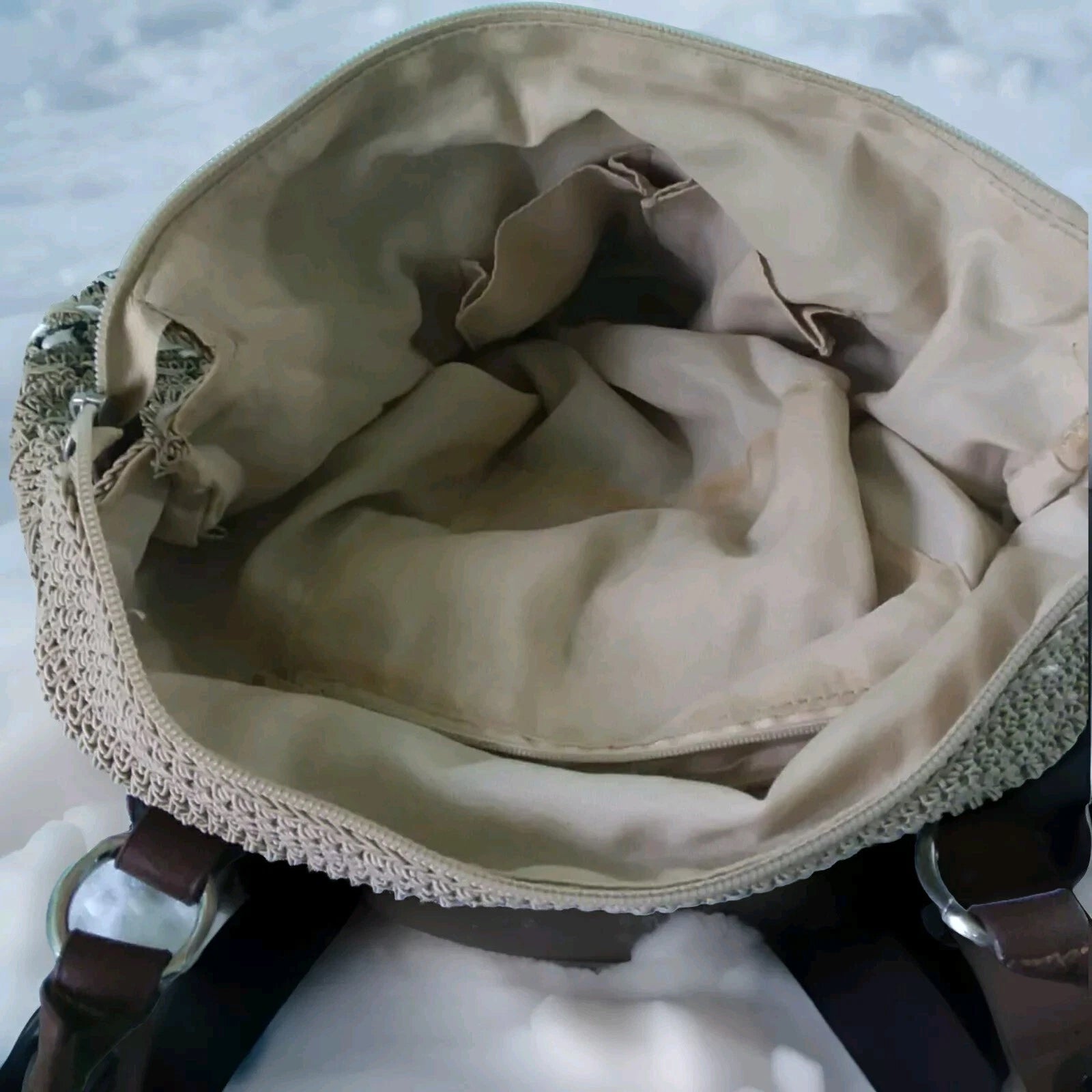 Beige handbag with brown interior on a light blue background