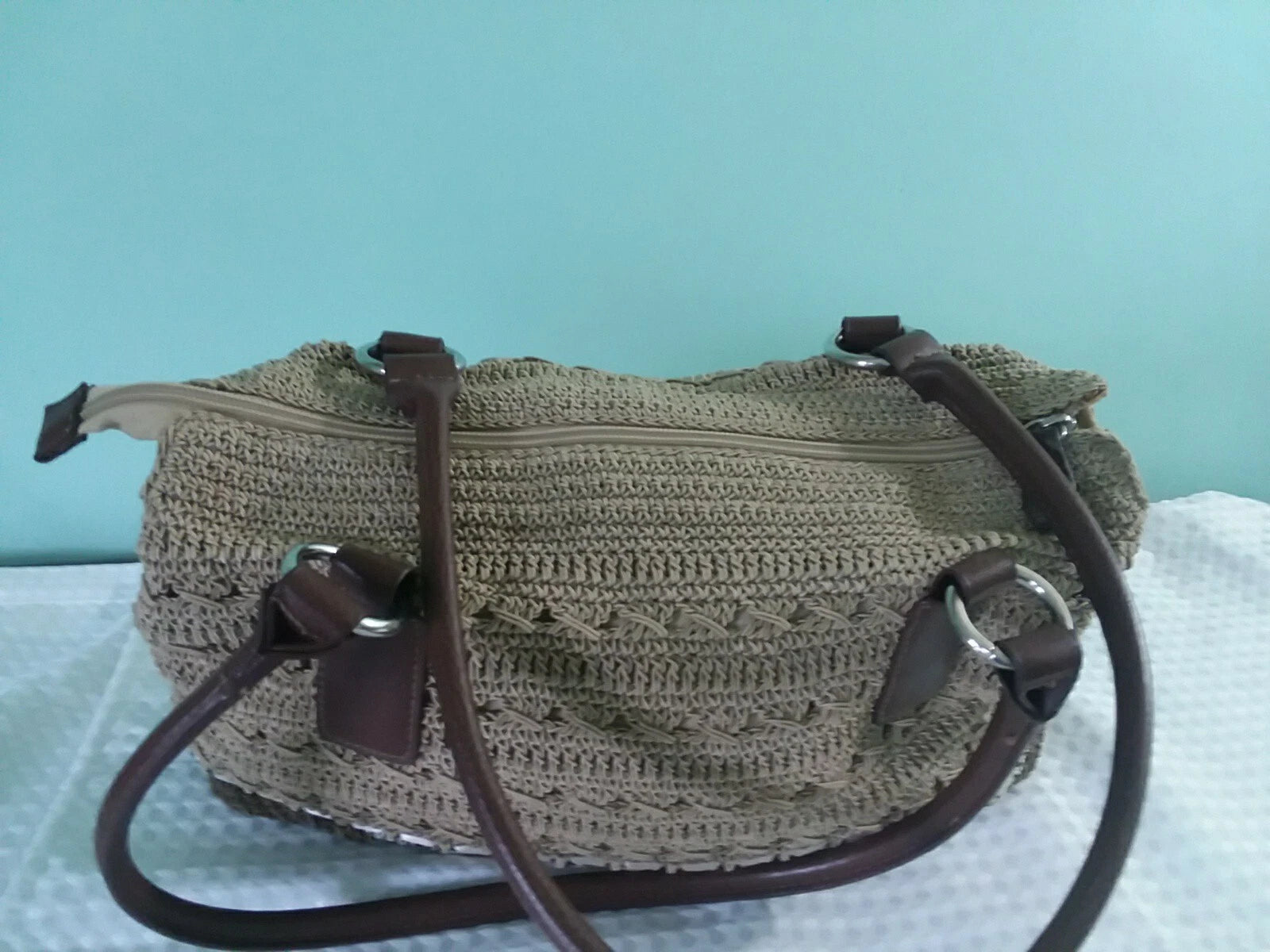 Crocheted handbag with brown straps on a light blue background