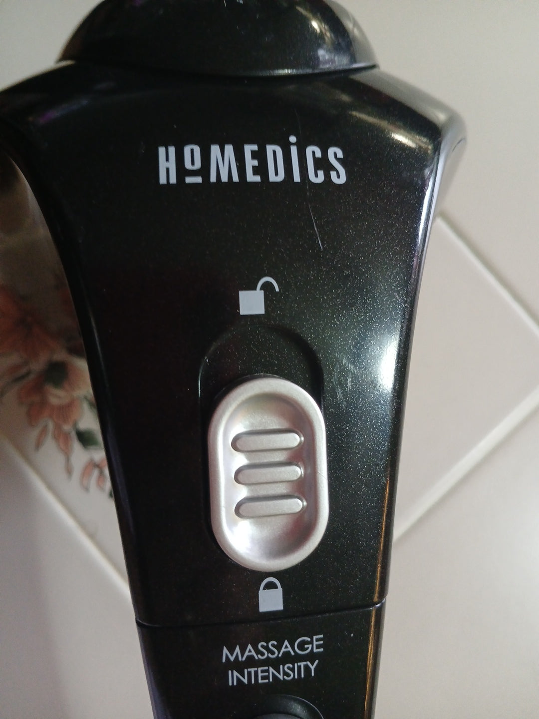 Homedics electronic device with control buttons on a tiled wall background