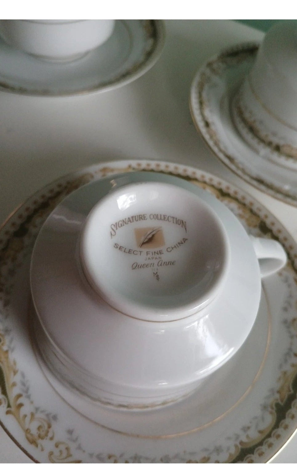 Close-up of a white teacup with gold detailing on a decorative saucer.