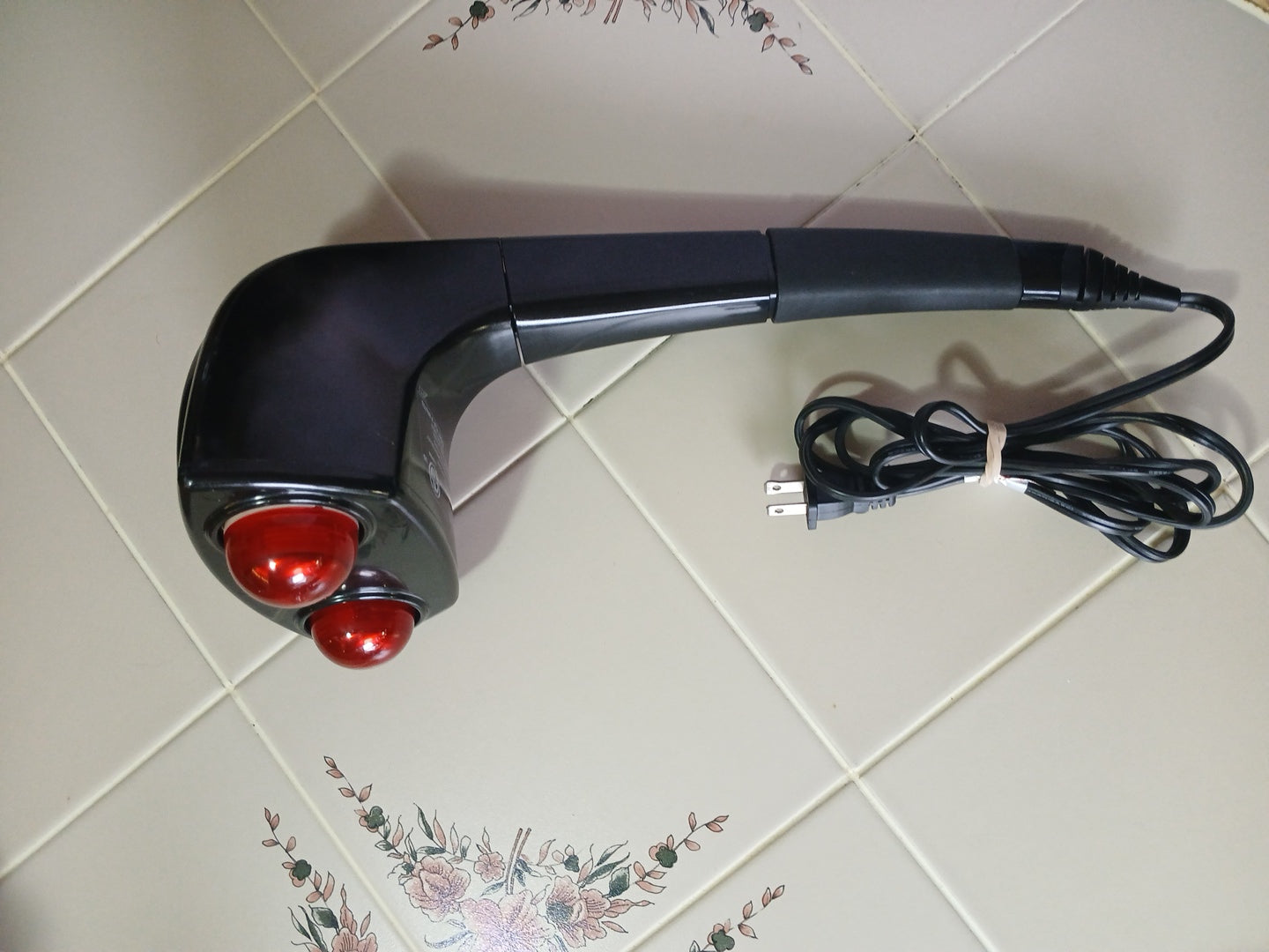 Black handheld device with red lights on a tiled floor