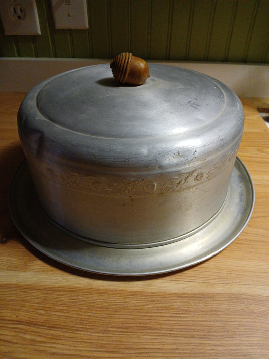 Metal cake saver with decorative handle on a wooden surface