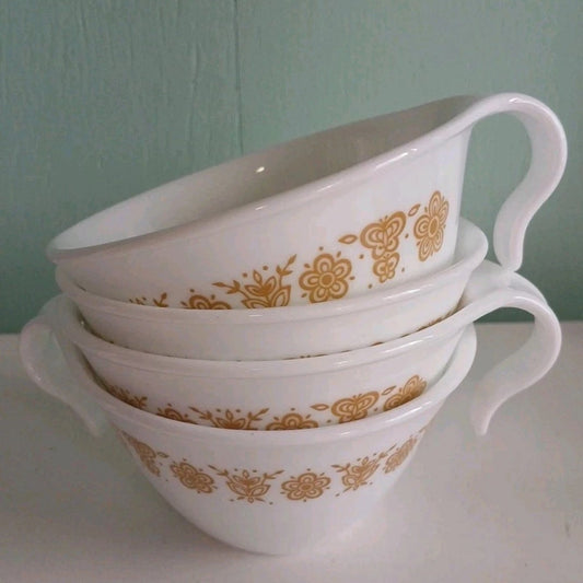 Stack of white cups with gold floral patterns on a light green background
