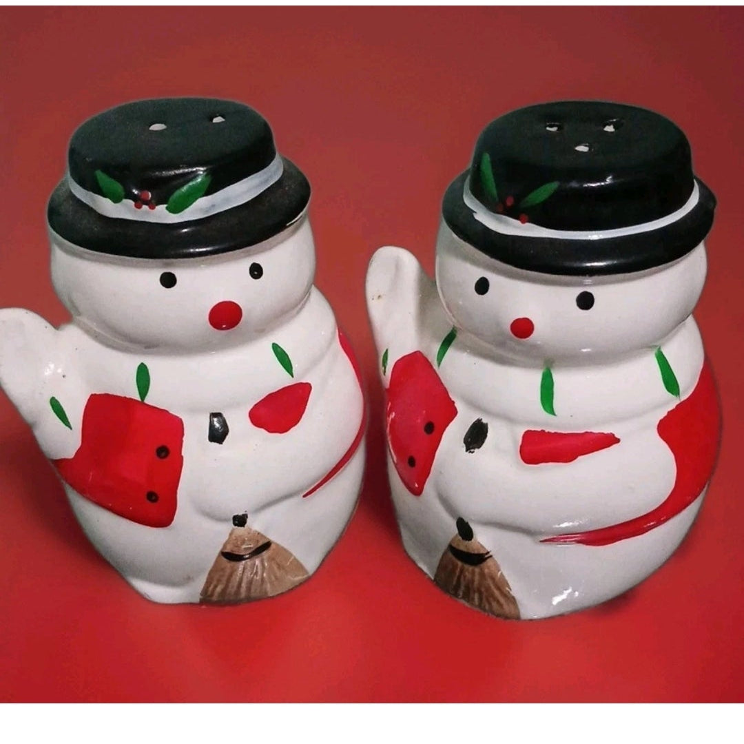 Two snowman-themed salt and pepper shakers on a red background