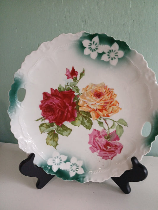 Decorative plate with floral design on a stand against a light green wall.
