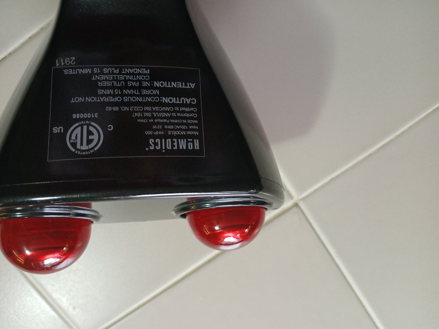 Black electronic device with red  massagers on a tiled floor