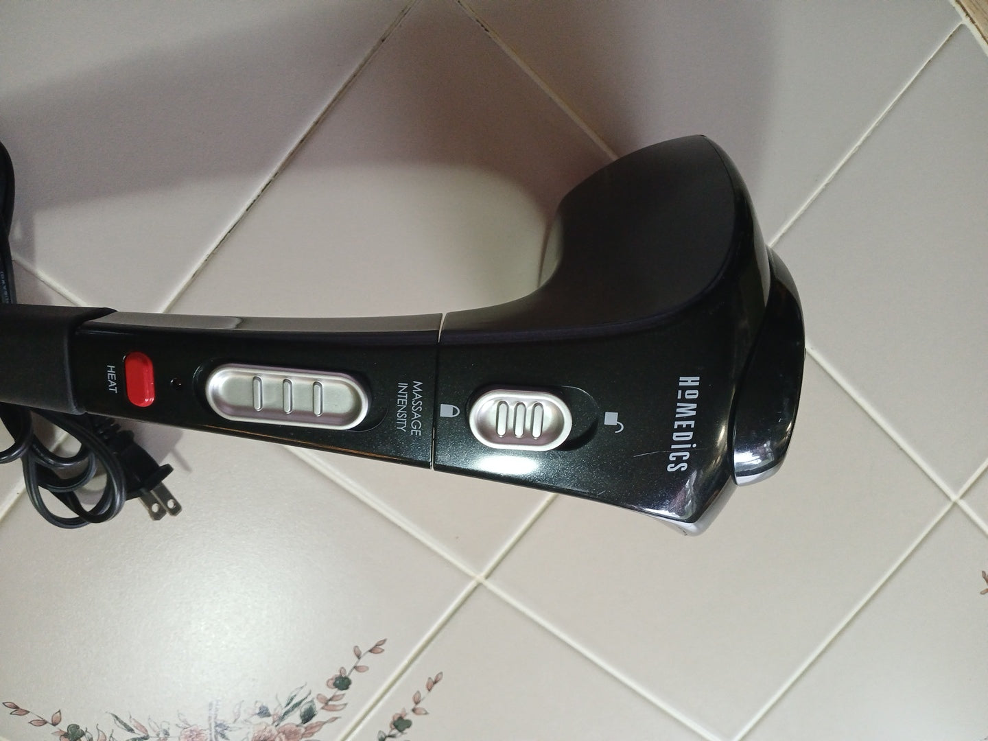 Black handheld device with control buttons on a tiled floor