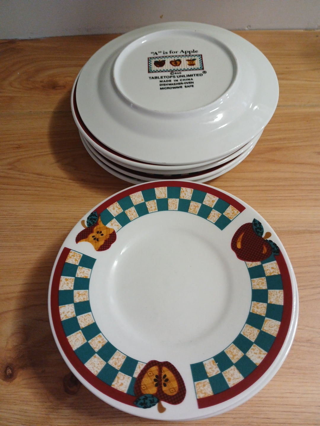 Set of ceramic plates with decorative borders and animal illustrations on a wooden surface.