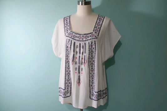 White blouse with embroidery on a mannequin against a light blue background