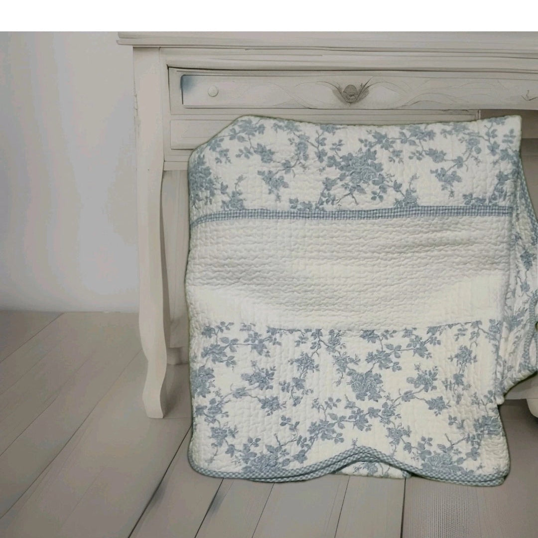 Floral-patterned quilt draped over a wooden bed frame.