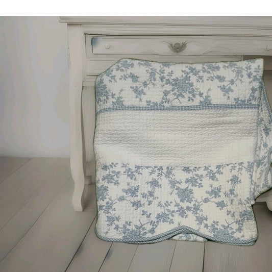 Floral-patterned quilt draped over a wooden bed frame.