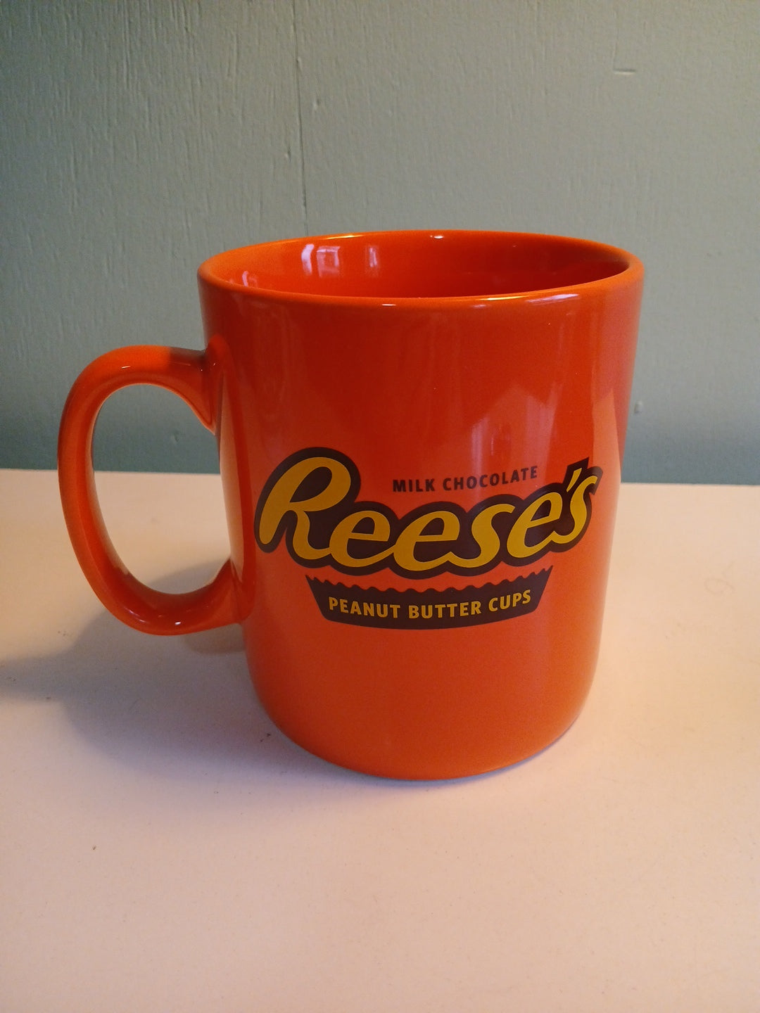 Orange mug with Reese's logo on a gray and white background