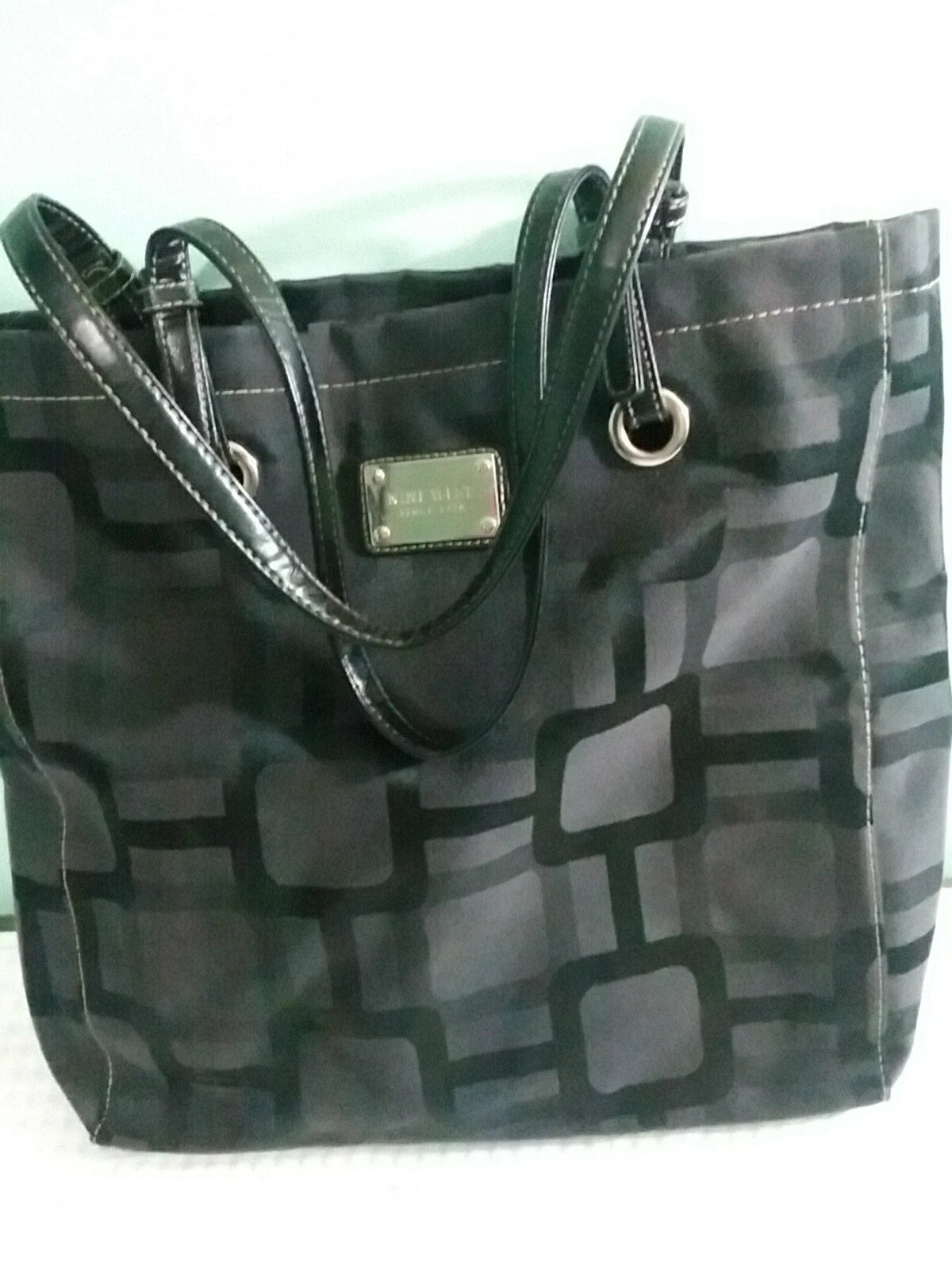 Black and gray patterned handbag with a visible brand label on a white background